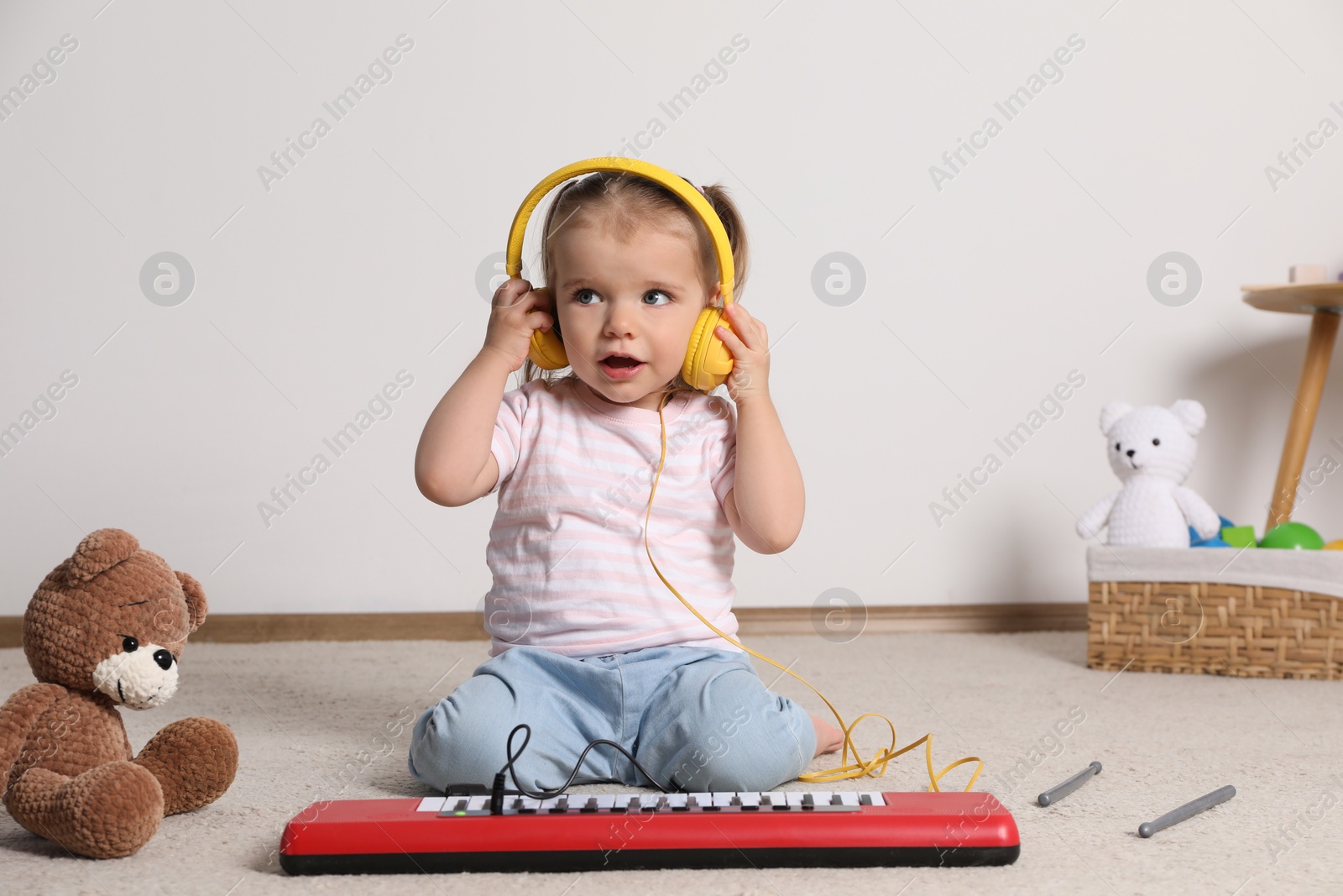 Photo of Cute little girl playing with toy piano at home