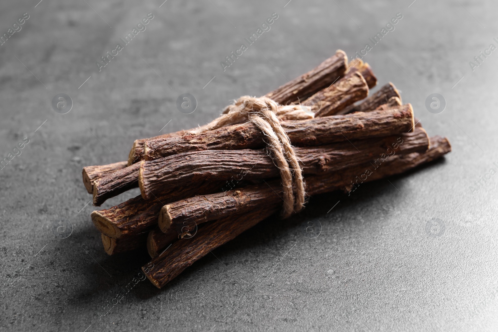 Photo of Dried sticks of liquorice root on grey table, closeup