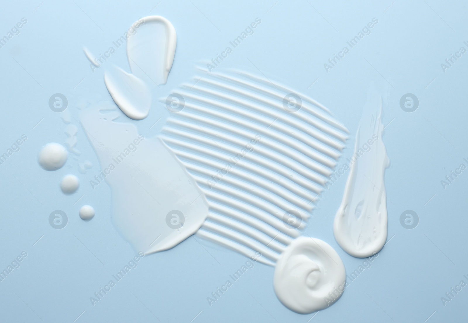 Photo of Samples of face cream on light blue background, top view