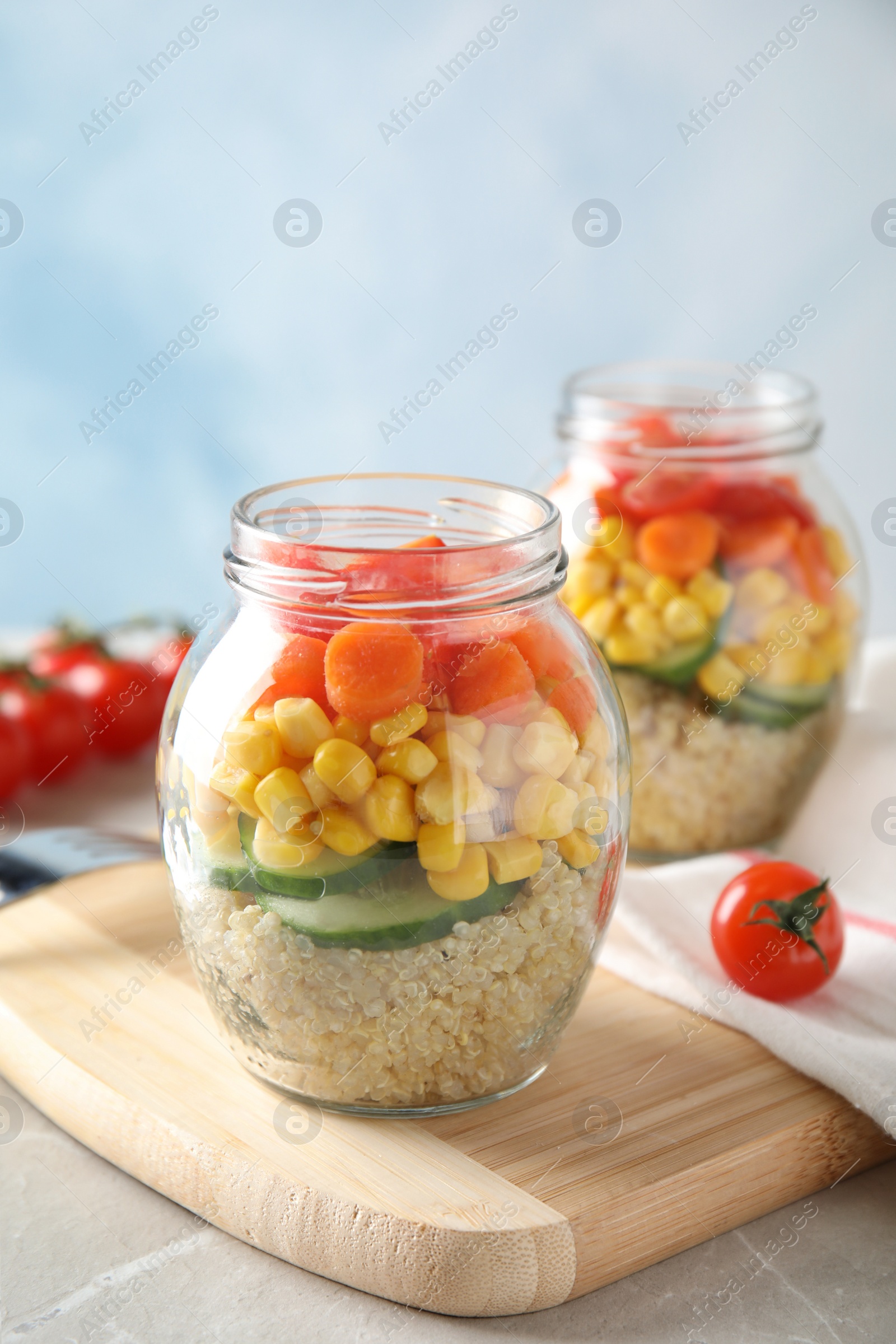 Photo of Jars with healthy quinoa salad and vegetables on table. Space for text