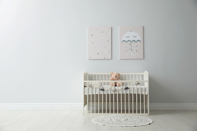 Photo of Minimalist room interior with baby crib, decor elements and toys. Space for text