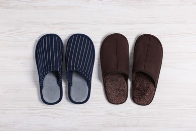 Different stylish slippers on white wooden floor, flat lay