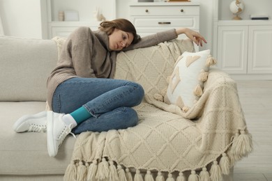 Sad young woman lying on sofa at home