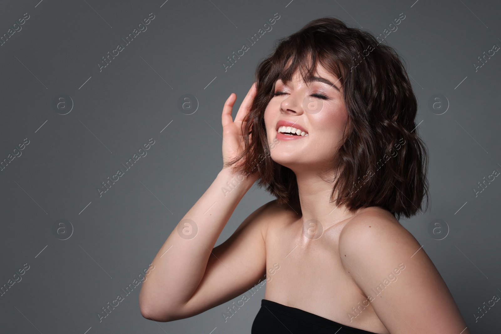 Photo of Portrait of beautiful young woman with wavy hairstyle on grey background. Space for text