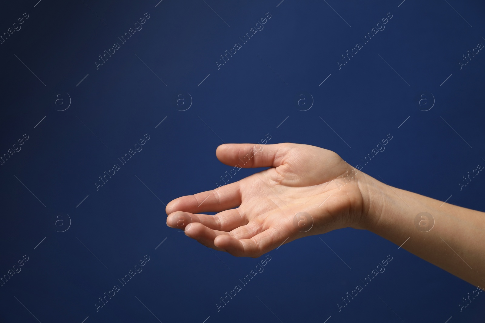 Photo of Woman holding something in hand on blue background, closeup