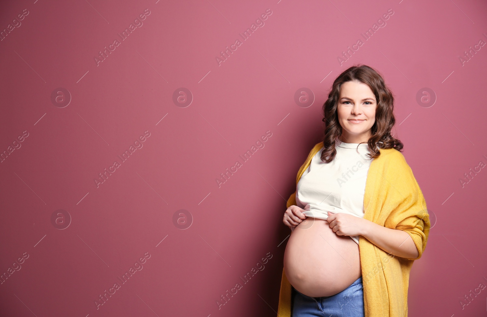 Photo of Young pregnant woman in casual clothes on color background