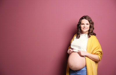 Young pregnant woman in casual clothes on color background