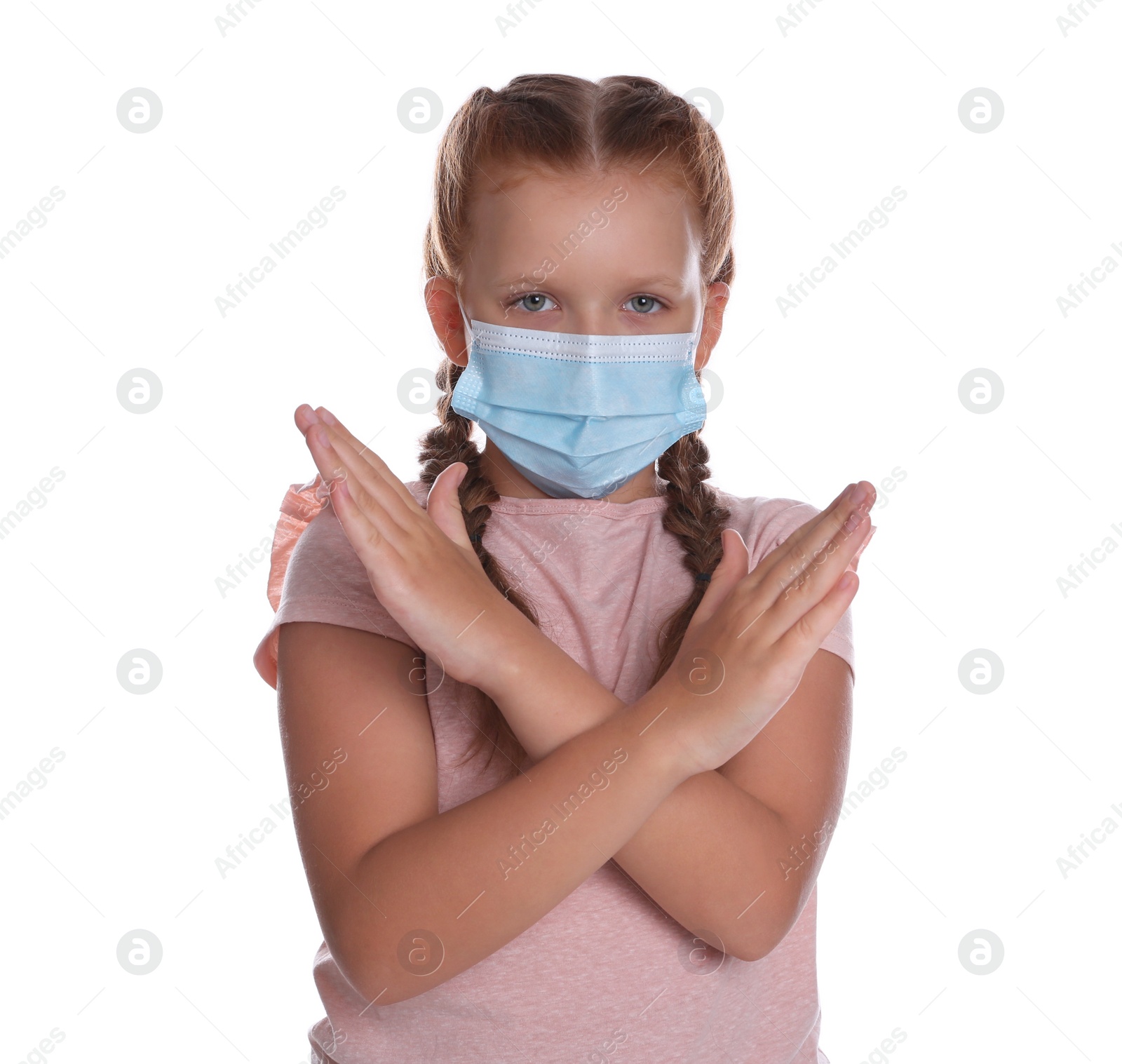 Photo of Little girl in protective mask showing stop gesture on white background. Prevent spreading of coronavirus