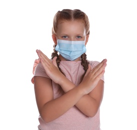 Photo of Little girl in protective mask showing stop gesture on white background. Prevent spreading of coronavirus