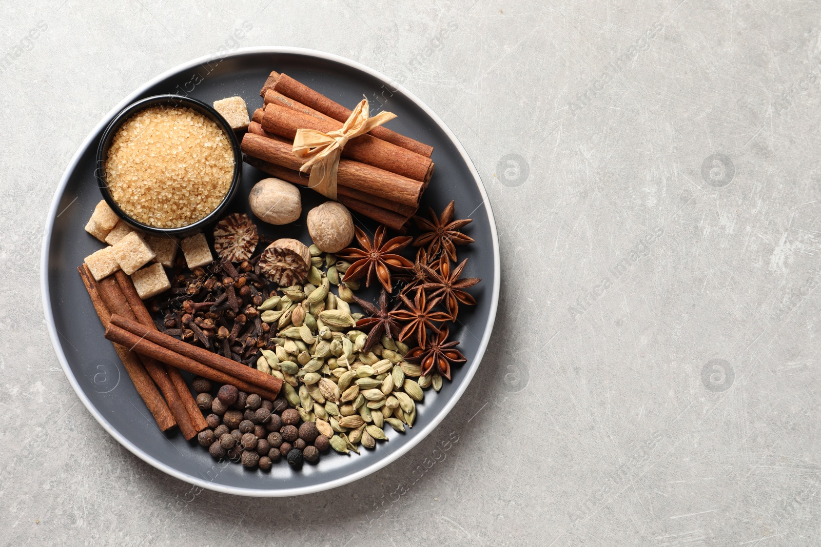 Photo of Plate with different aromatic spices on light textured table, top view. Space for text