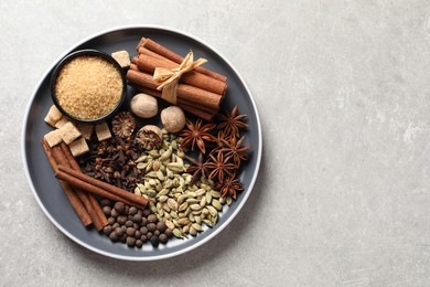 Photo of Plate with different aromatic spices on light textured table, top view. Space for text