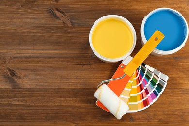 Photo of Buckets of paints, palette and roller on wooden background, flat lay. Space for text