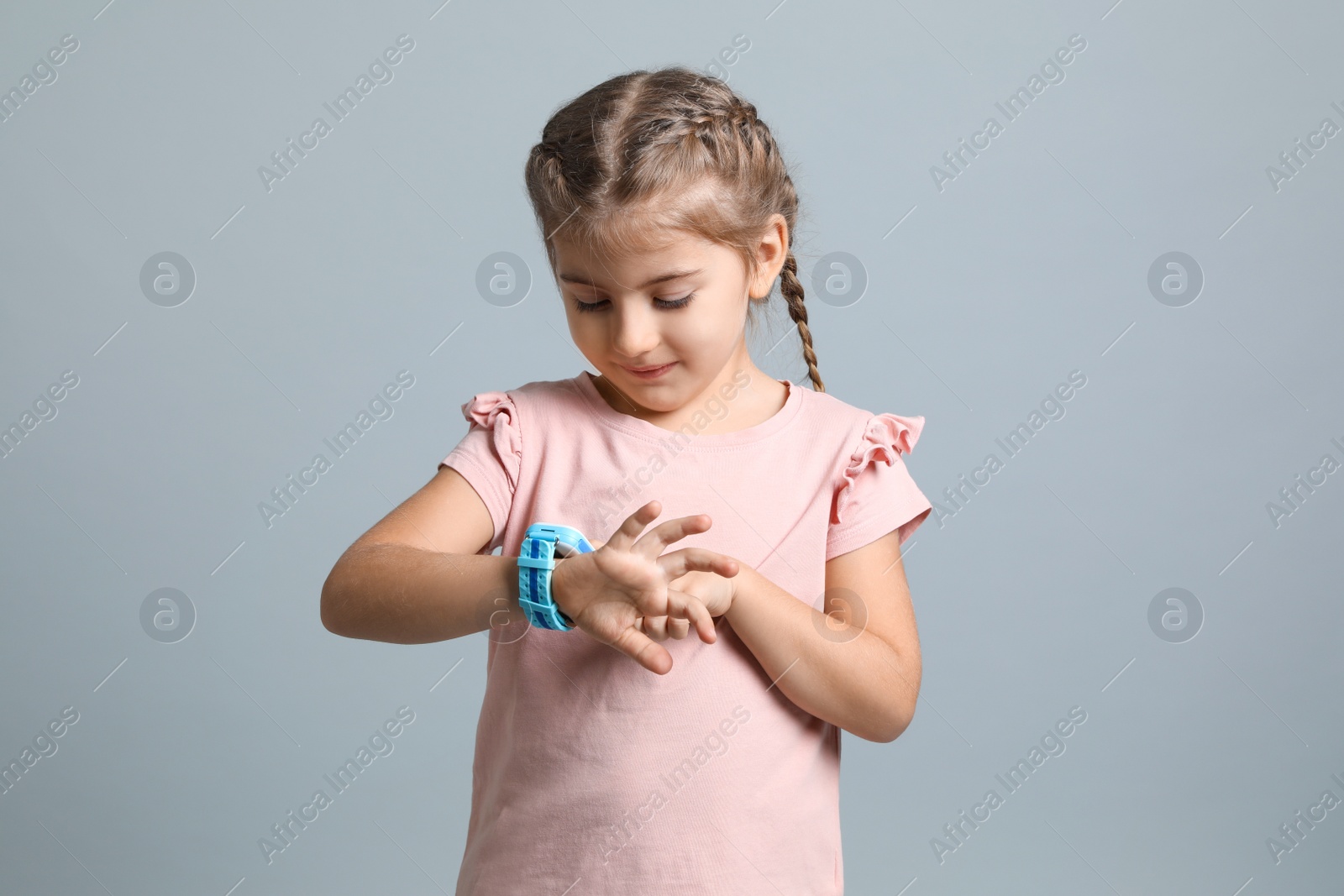 Photo of Little girl with smart watch on grey background