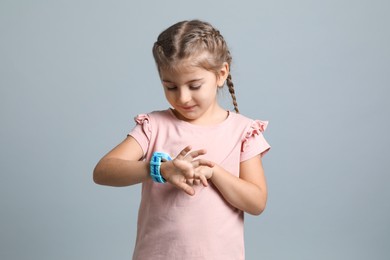 Little girl with smart watch on grey background