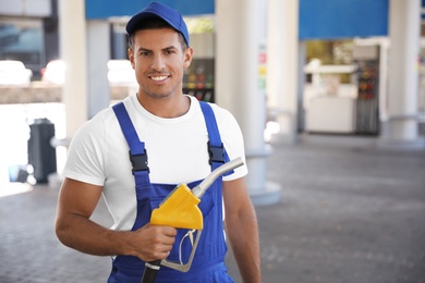 Photo of Worker with fuel pump nozzle at gas station