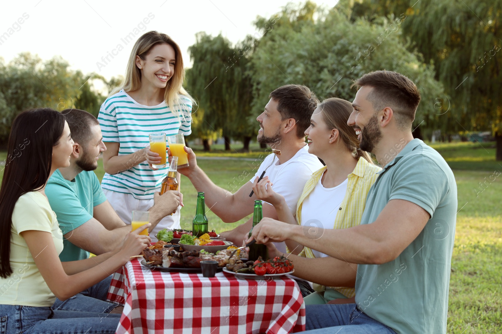 Photo of Happy friends with drinks and food at barbecue party in park