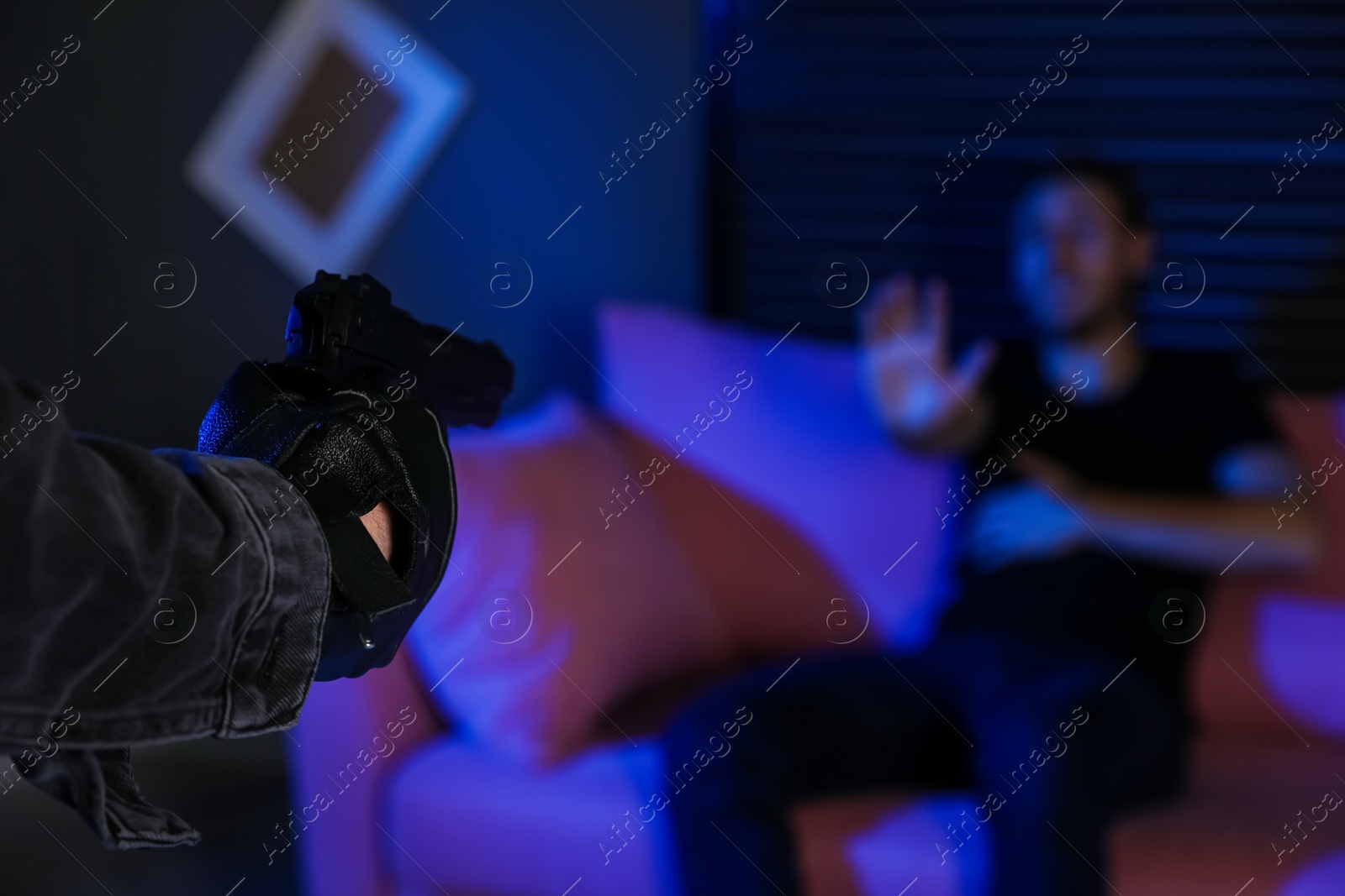 Photo of Man aiming his victim with gun in dark room, closeup. Dangerous criminal