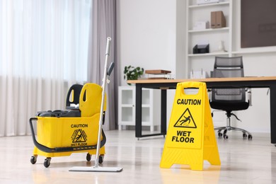 Photo of Cleaning service. Mop, bucket and wet floor sign in office