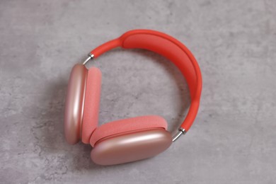 Stylish pink headphones on light grey table, closeup