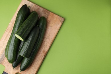 Fresh cucumbers on green background, top view. Space for text