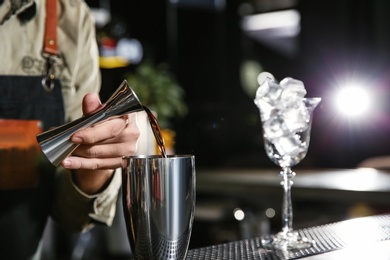 Photo of Barman pouring martini into shaker on counter, closeup with space for text