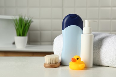 Photo of Baby cosmetic products, bath duck, brush and towel on white table. Space for text