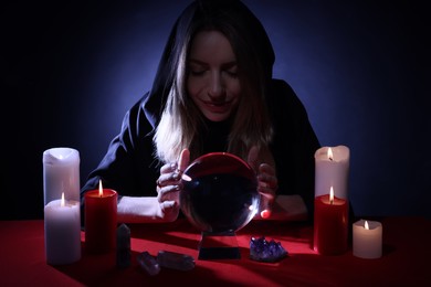 Soothsayer using crystal ball to predict future at table in darkness. Fortune telling