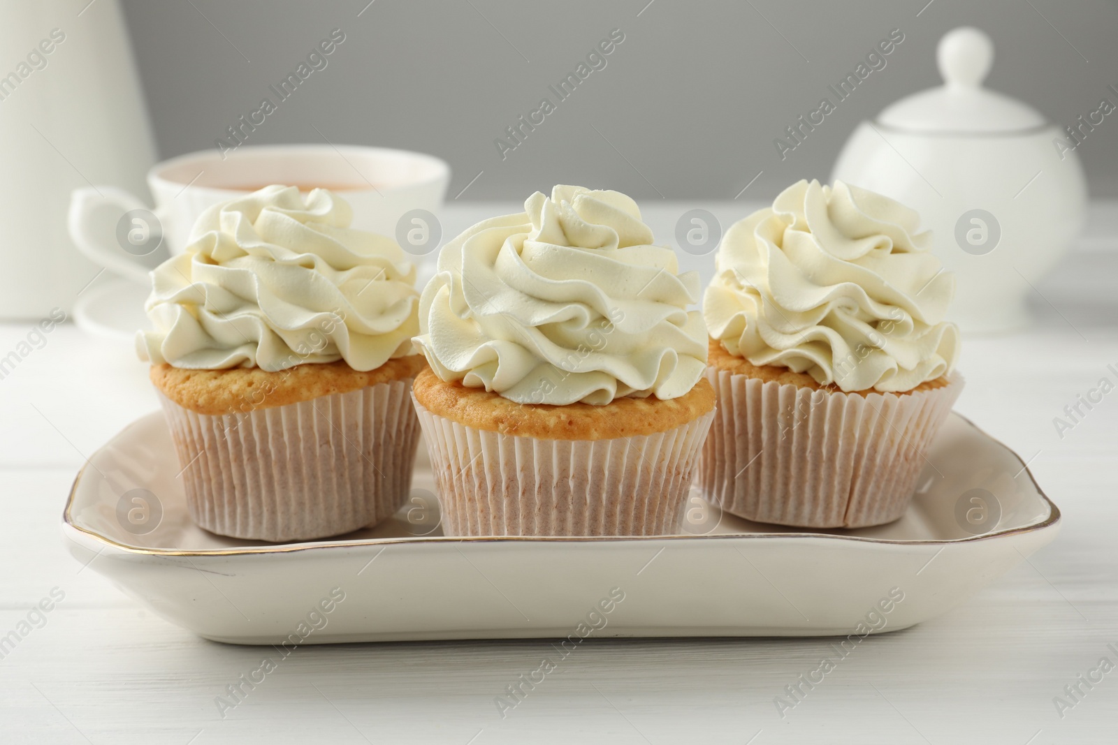 Photo of Tasty cupcakes with vanilla cream on white wooden table, closeup