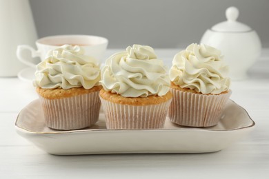 Photo of Tasty cupcakes with vanilla cream on white wooden table, closeup