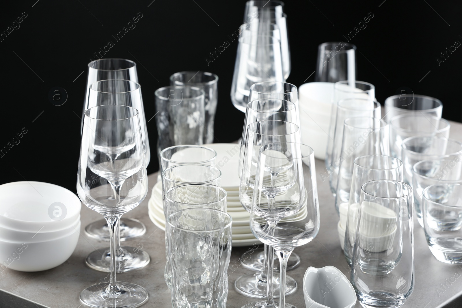 Photo of Set of empty glasses and dishware on table against black background