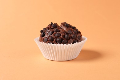 Photo of One tasty chocolate muffin on pale orange background