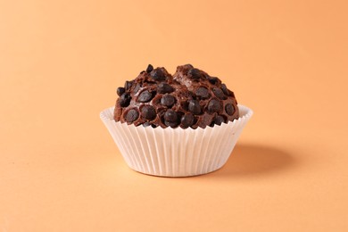 One tasty chocolate muffin on pale orange background