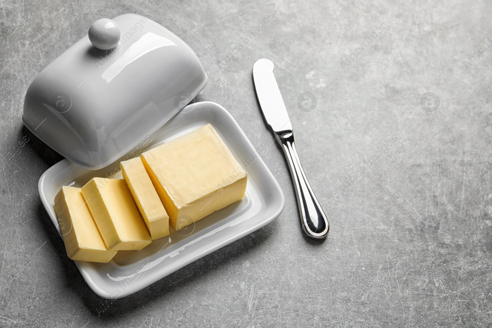 Photo of Dish with fresh butter and knife on table. Space for text