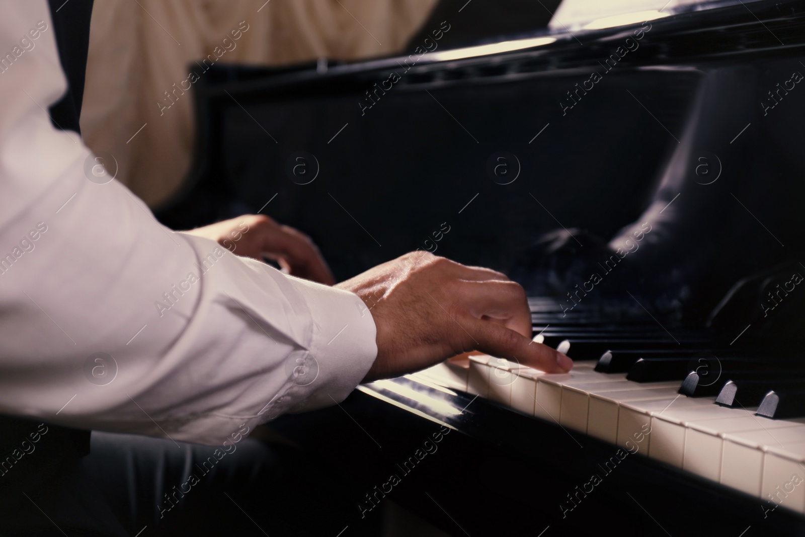 Photo of Man playing piano indoors, closeup. Talented musician