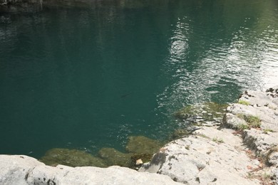 Picturesque view of clean pond near stones outdoors