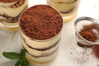 Photo of Delicious tiramisu in glasses and mint on table, above view