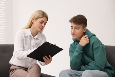 Psychologist working with teenage boy in office