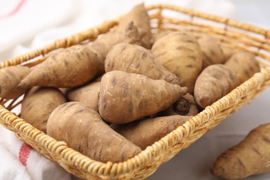 Photo of Tubers of turnip rooted chervil in wicker basket on table, closeup