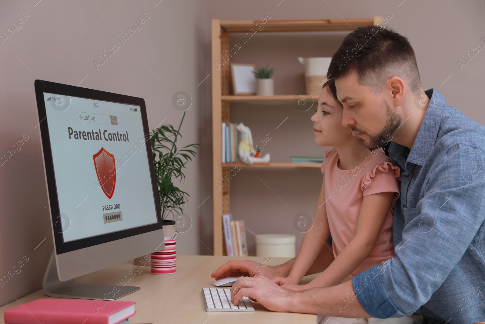 Photo of Dad installing parental control on computer at table indoors. Child safety