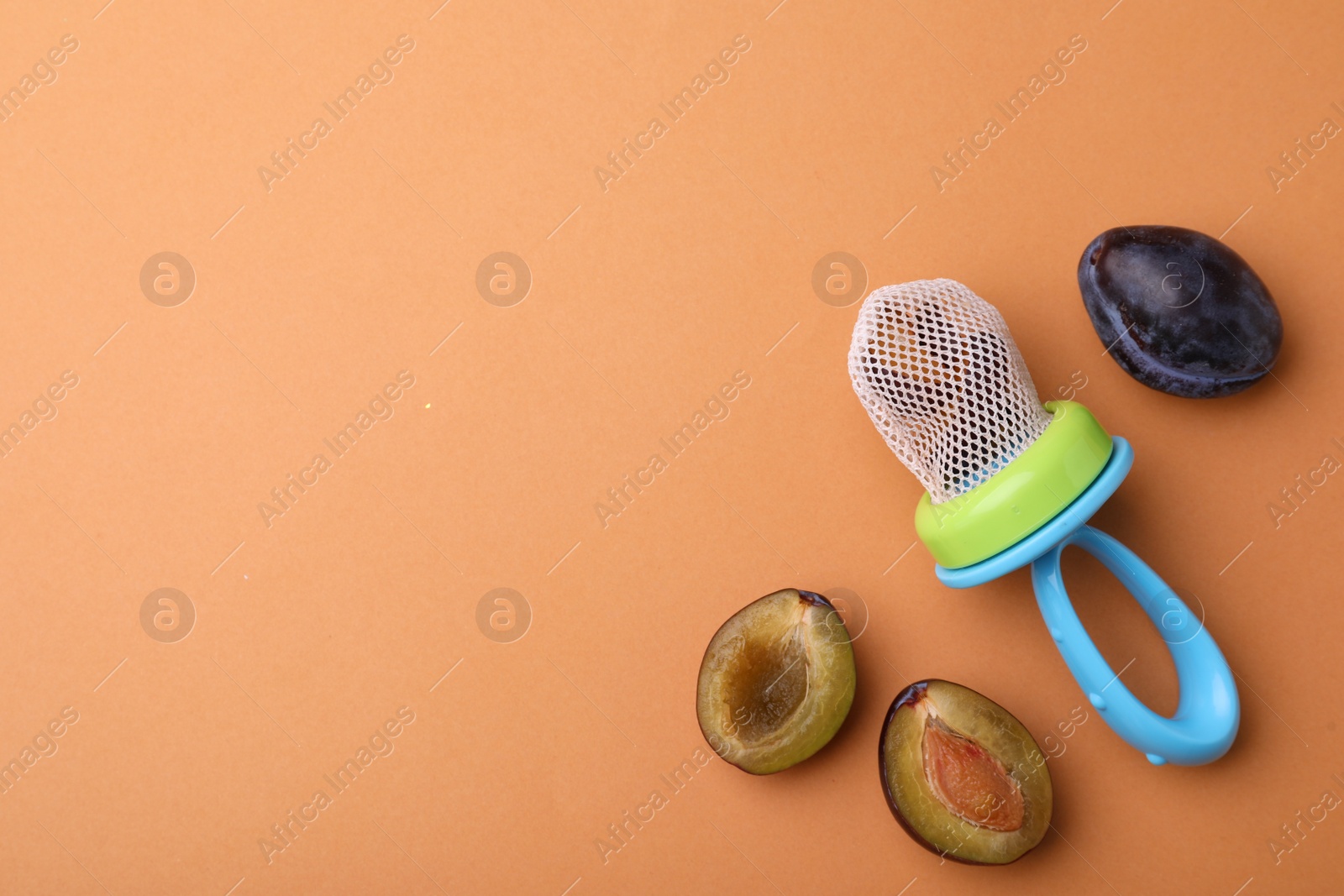 Photo of Nibbler with fresh plum on pale orange background, flat lay. Space for text