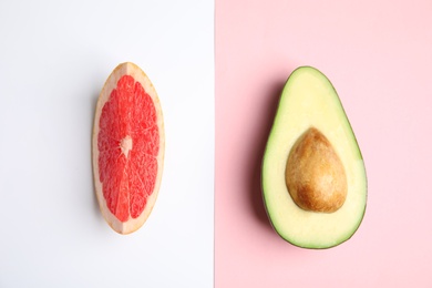 Cut ripe avocado and grapefruit on color background, flat lay