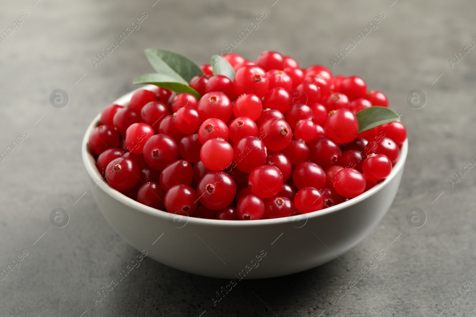 Photo of Ripe fresh cranberry in bowl on grey table