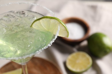 Delicious Margarita cocktail with ice cubes in glass and lime, closeup. Space for text