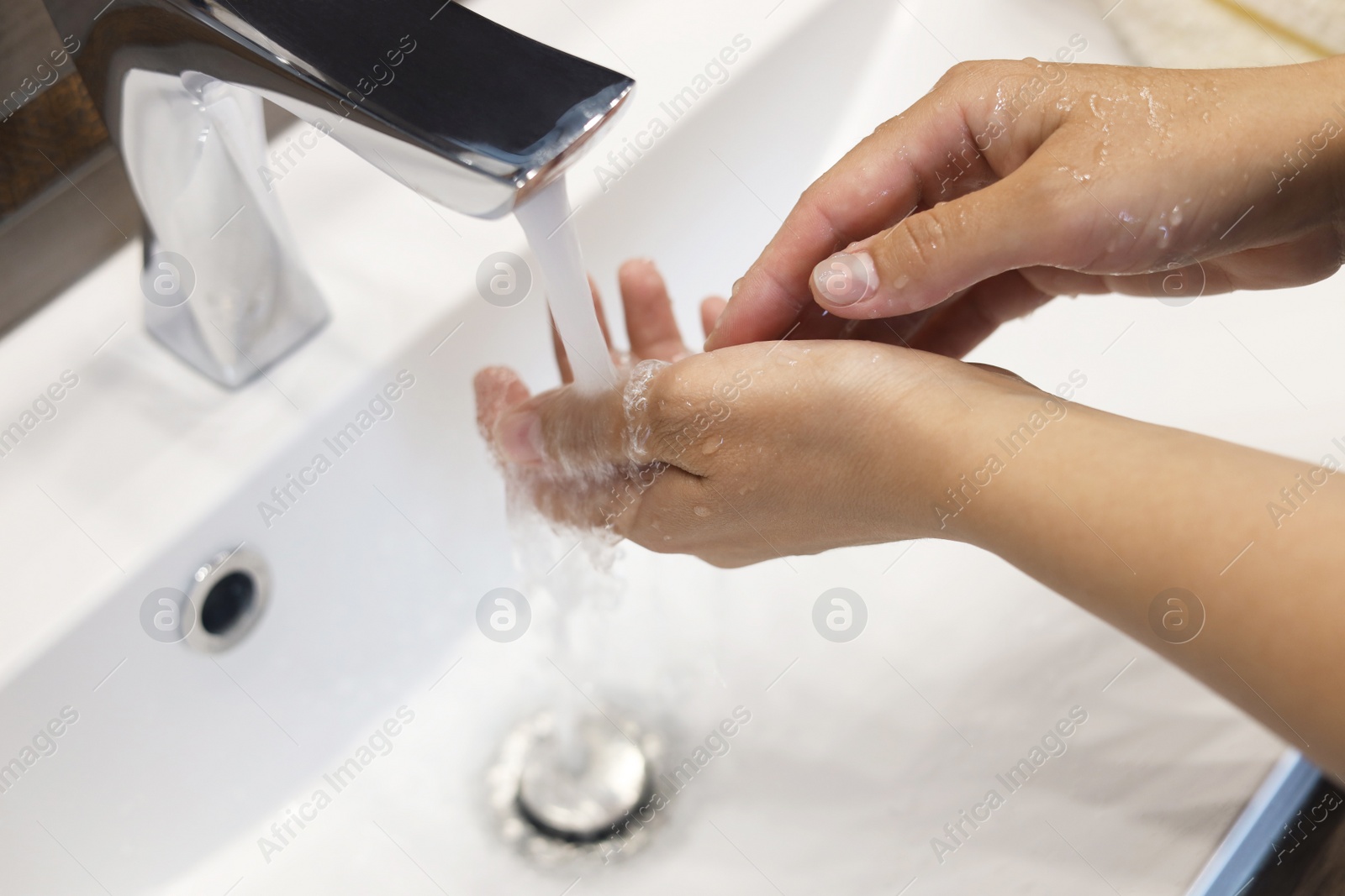 Photo of Woman washing hands in sink, closeup view