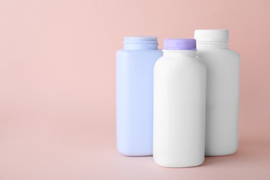 Photo of Baby powder in bottles on light coral background, space for text