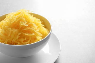 Bowl with cooked spaghetti squash on grey background. Space for text