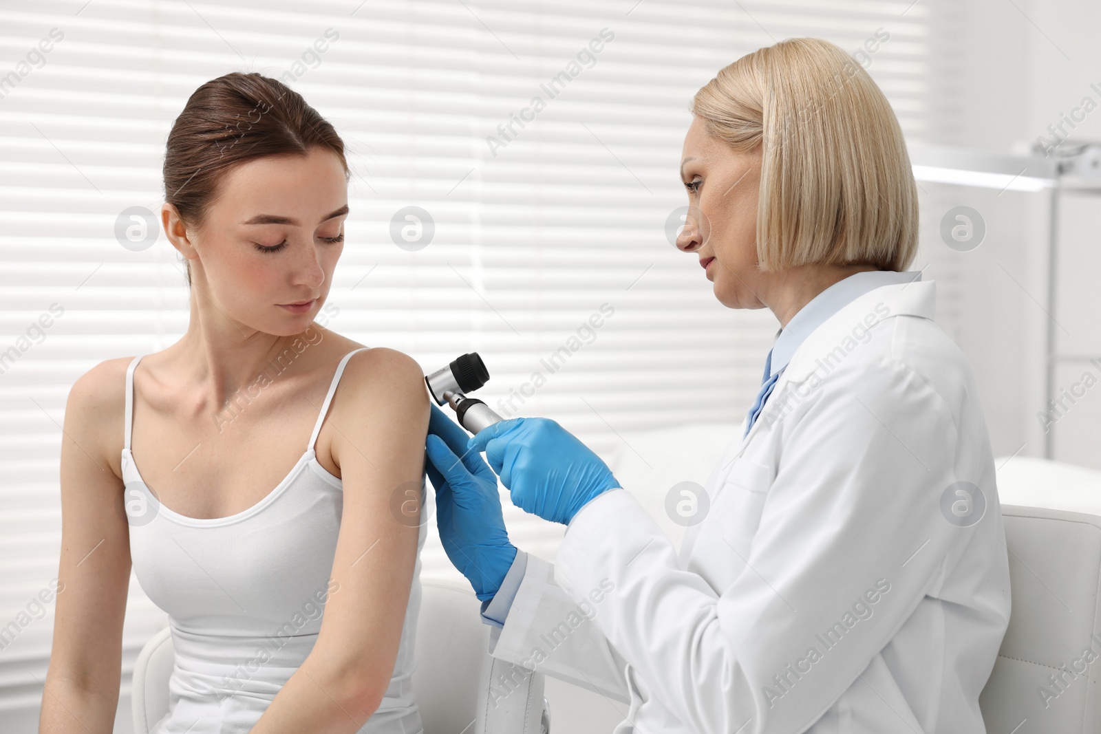 Photo of Dermatologist with dermatoscope examining patient in clinic