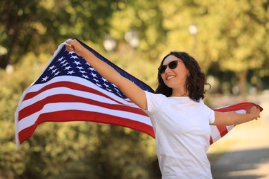 Photo of Happy young woman with American flag in park on sunny day