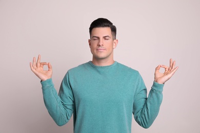 Photo of Man meditating on light background. Stress relief exercise