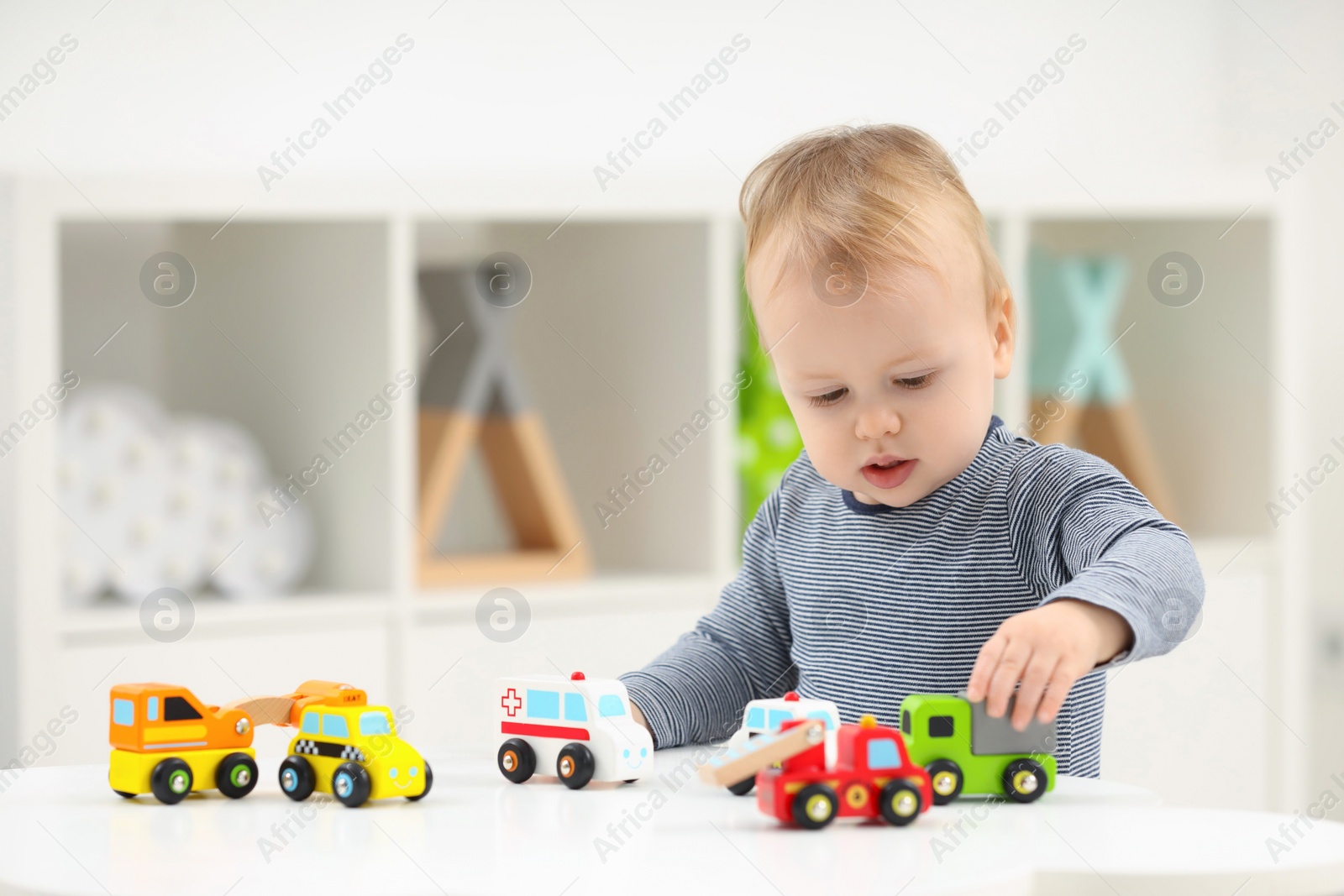 Photo of Children toys. Cute little boy playing with toy cars at white table in room, space for text